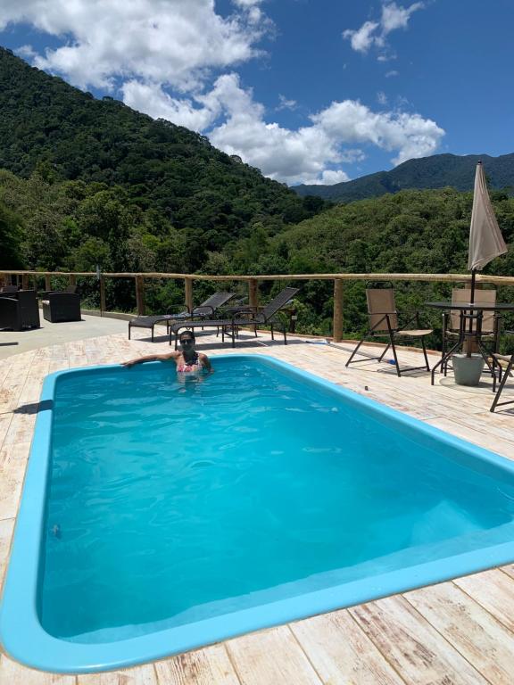 una persona en una piscina con montañas en el fondo en Casa para temporada em meio à natureza., en Cachoeiras de Macacu