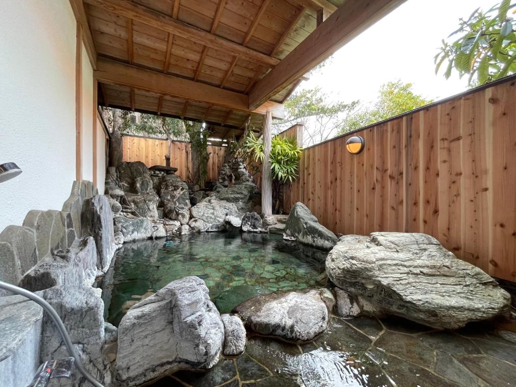 a pool of water with rocks in a backyard at 源泉かけ流しの露天風呂を独り占め！一棟貸切旅館「御宿あさか」29名まで宿泊可 in Ena