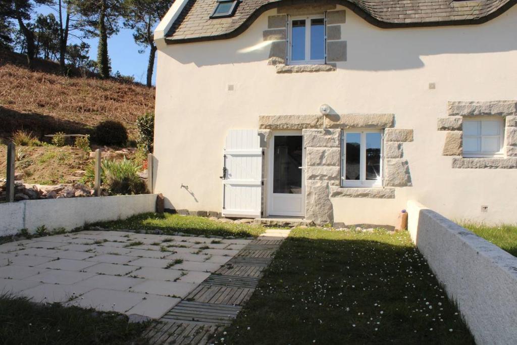 une maison avec une passerelle en pierre devant elle dans l'établissement 701 - Maison face à la plage au domaine de LANRUEN, à Erquy, à Le Val