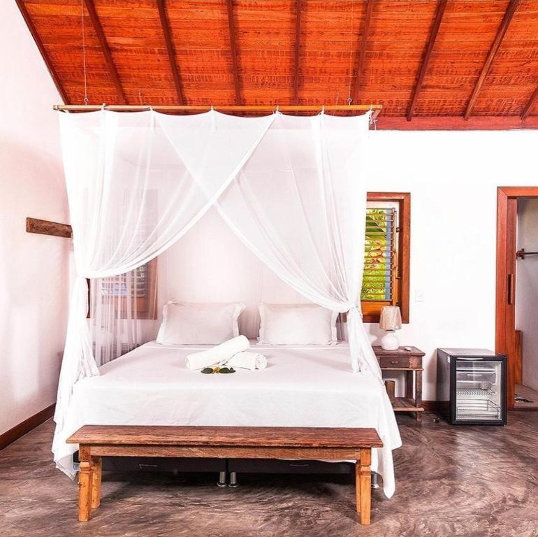 a bedroom with a white bed with a canopy at Casa Bora Lá in Caraíva