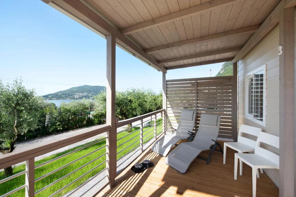 een veranda met witte stoelen en uitzicht op het water bij Camping Eurovil in Predore