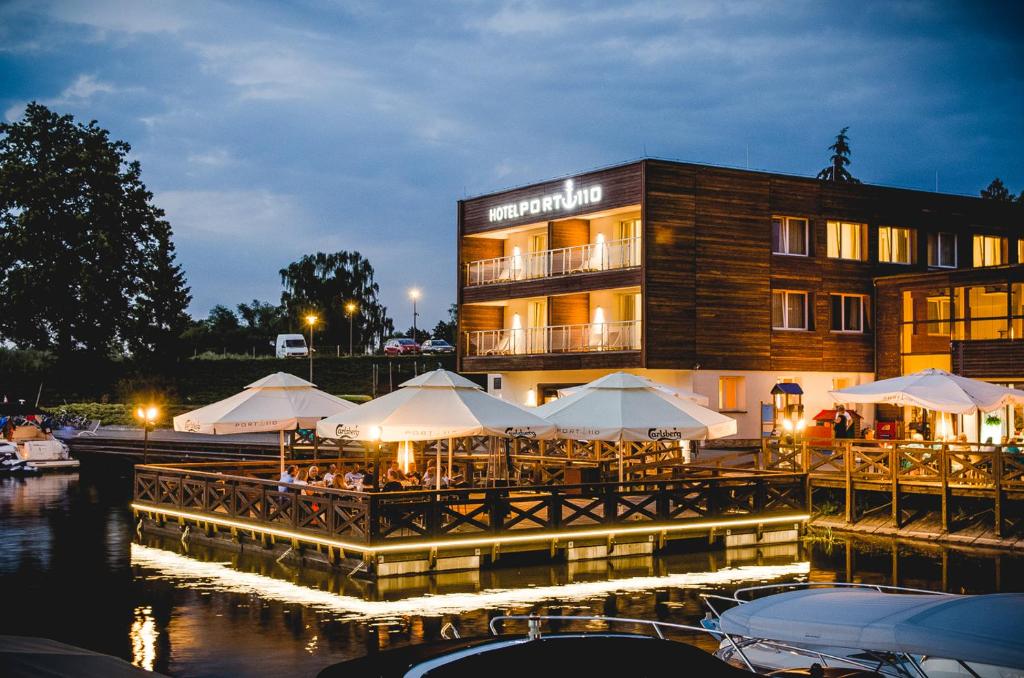 een restaurant met tafels en witte parasols voor een gebouw bij Hotel Port 110 in Iława