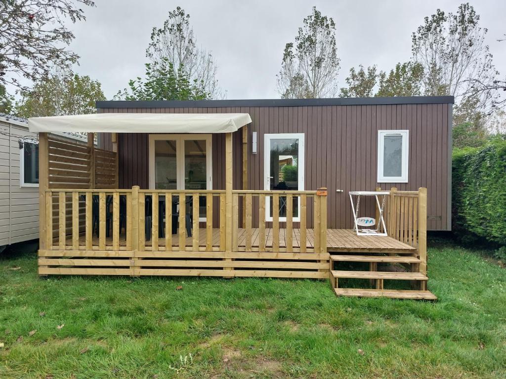 een tiny house met een terras en een veranda bij Mobil home 7 couchages in Ouistreham