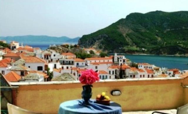 a vase on a table with a view of a town at Aperanto Galazio in Skopelos Town