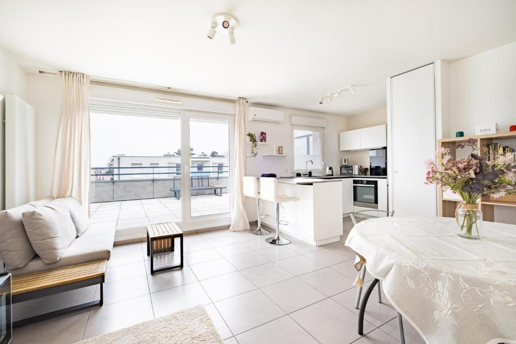 Il comprend un salon blanc avec une table et une cuisine. dans l'établissement Appartement T2 neuf - Grande Terrasse de 25m2, à Saint-Priest