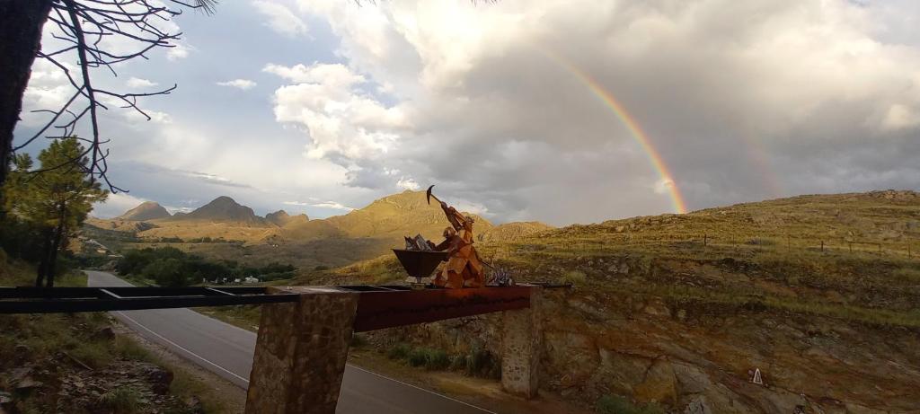 un arco iris en el cielo sobre un camino con una colina en La Francisca en La Carolina