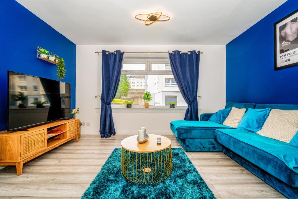 Sala de estar azul con sofá azul y TV en A Gem in Greenock - Sleeps 8, en Greenock