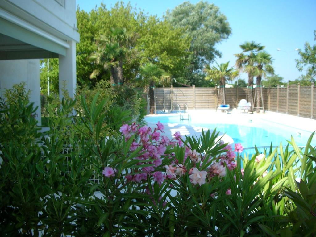 une arrière-cour avec une piscine et quelques fleurs dans l'établissement Residence Le Palme, à Lido di Jesolo