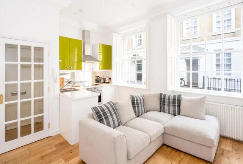 a living room with a white couch and a kitchen at Orchard Street: 1BR with Garden in Bath