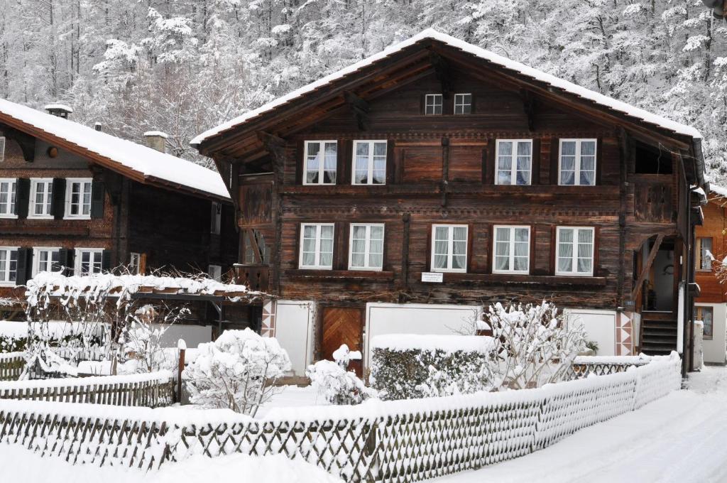 a wooden house with a fence in the snow at Chalet Huber 6-Bettwohnung in Meiringen