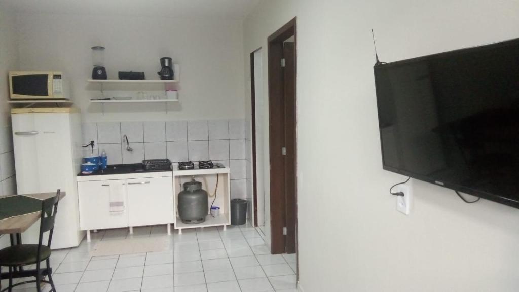 a kitchen with a television and a kitchen with a stove at Apto 03 - 1 quarto com 2 camas solteiro e garagem, possui ventilador de teto in Cascavel