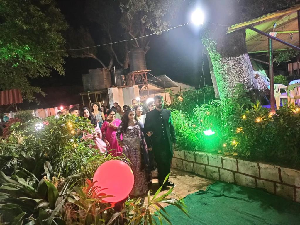 a bride and groom walking down the aisle at a wedding at night at PARK RESORT MATHERAN in Matheran