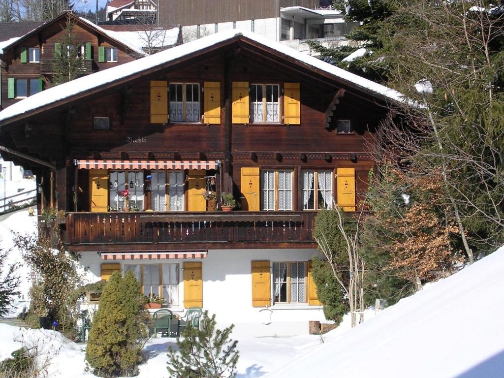 een groot houten huis met een balkon in de sneeuw bij Birkli 2, 2 Bett Wohnung in Wengen