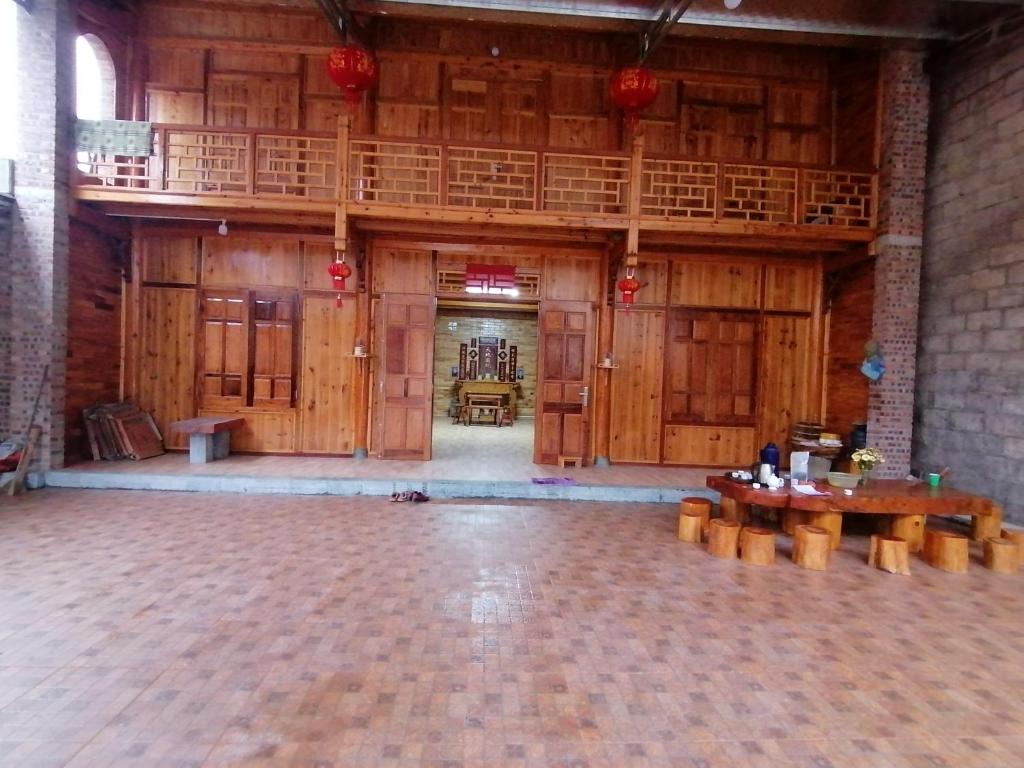 a large room with wooden walls and tables and a balcony at Phố Bảng Homestay in Pho Bang