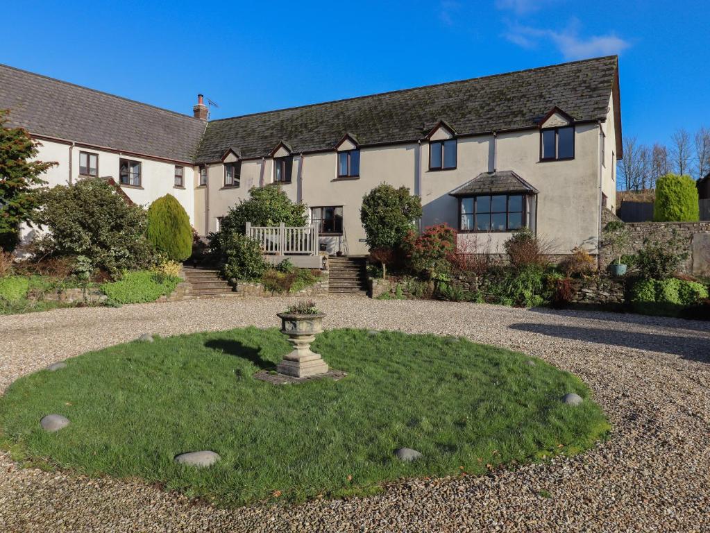 a large white house with a statue in the yard at Dairy Cottage in South Molton