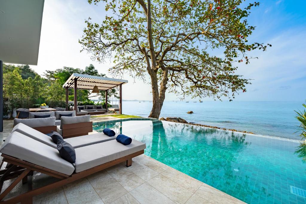 a pool with a couch and chairs next to the ocean at Kove Samui in Koh Samui 