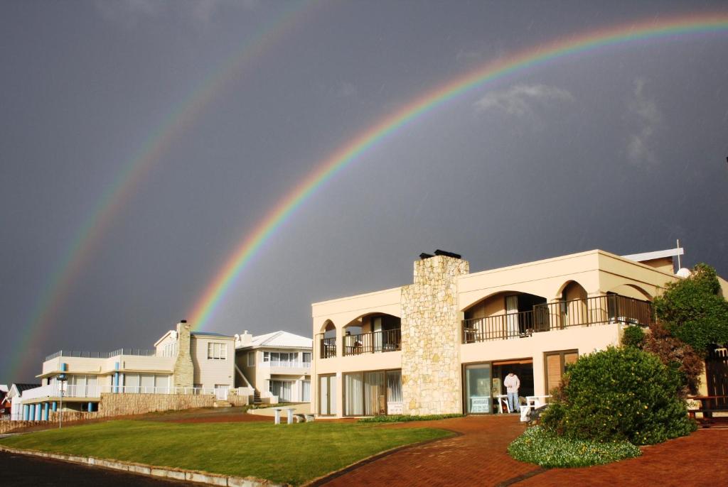 a rainbow in the sky above a building at Beachcastle in Stilbaai
