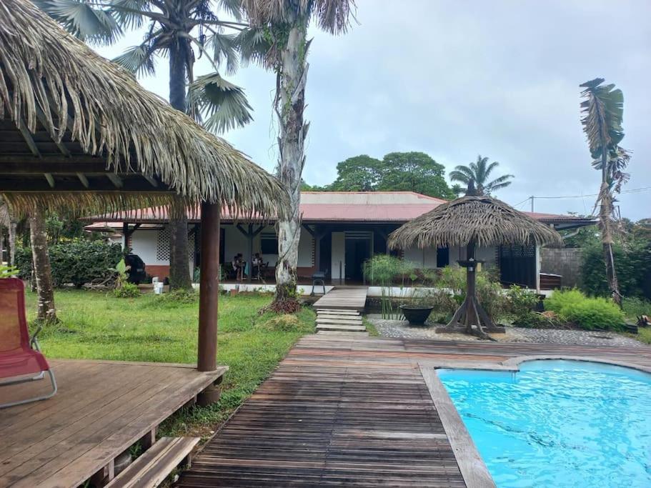 een resort met een houten loopbrug en een zwembad bij La Villa des Palmiers Bleus - Piscine & Jardin in Matoury