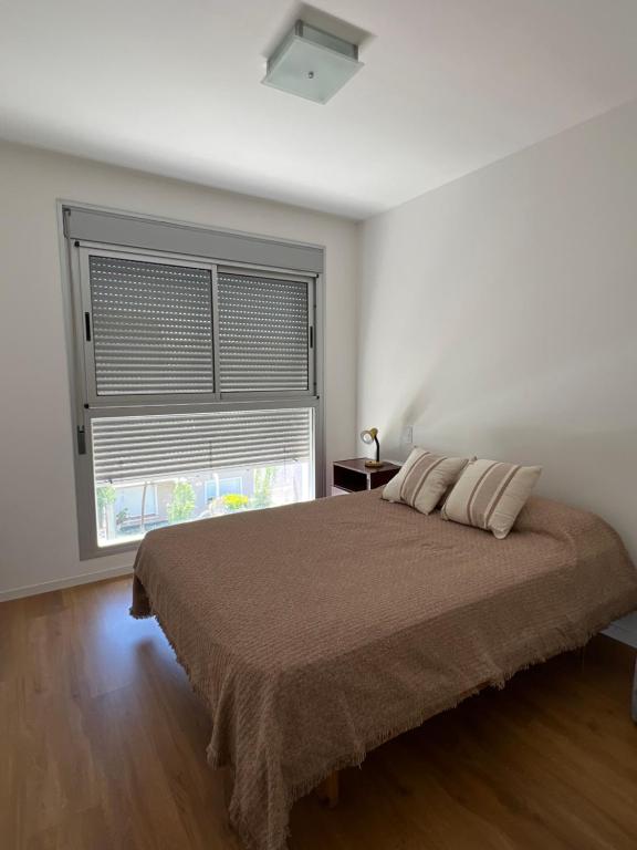 um quarto com uma cama e uma grande janela em Departamento amoblado 1 dormitorio Familiar em Bahía Blanca