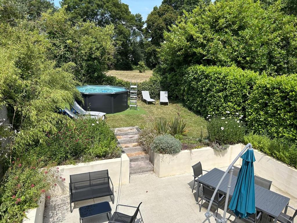 un patio avec une table et des chaises et une piscine dans l'établissement 903 - Magnifique longère entièrement rénovée quelques kilomètres des plages d'Erquy, à Erquy