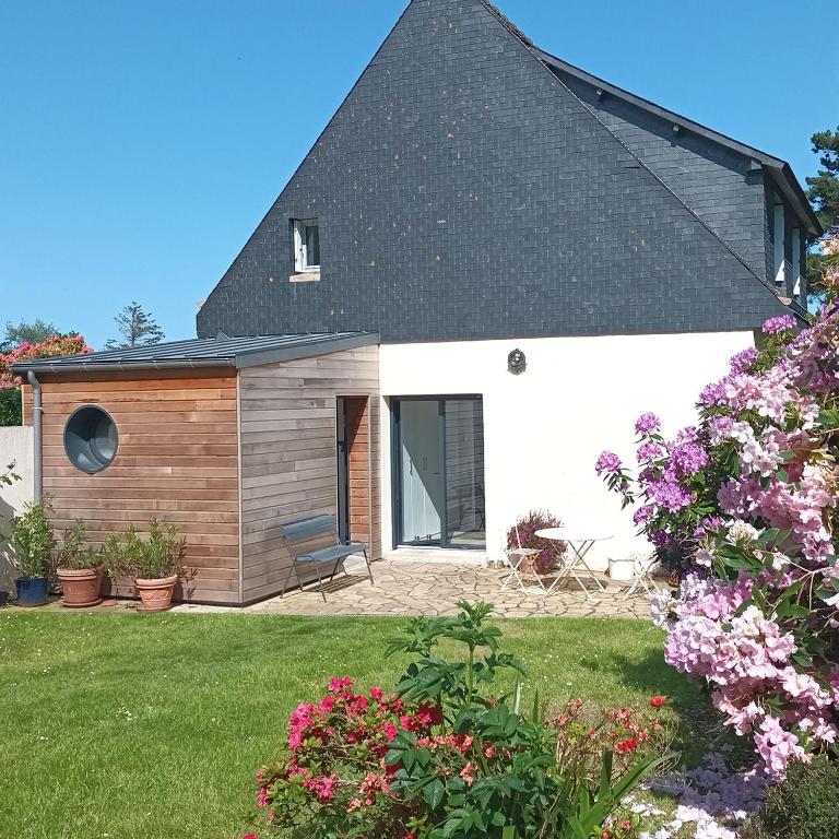une maison avec un toit noir et quelques fleurs dans l'établissement Ty Sklaer, à 200 m de la mer, à Penvénan