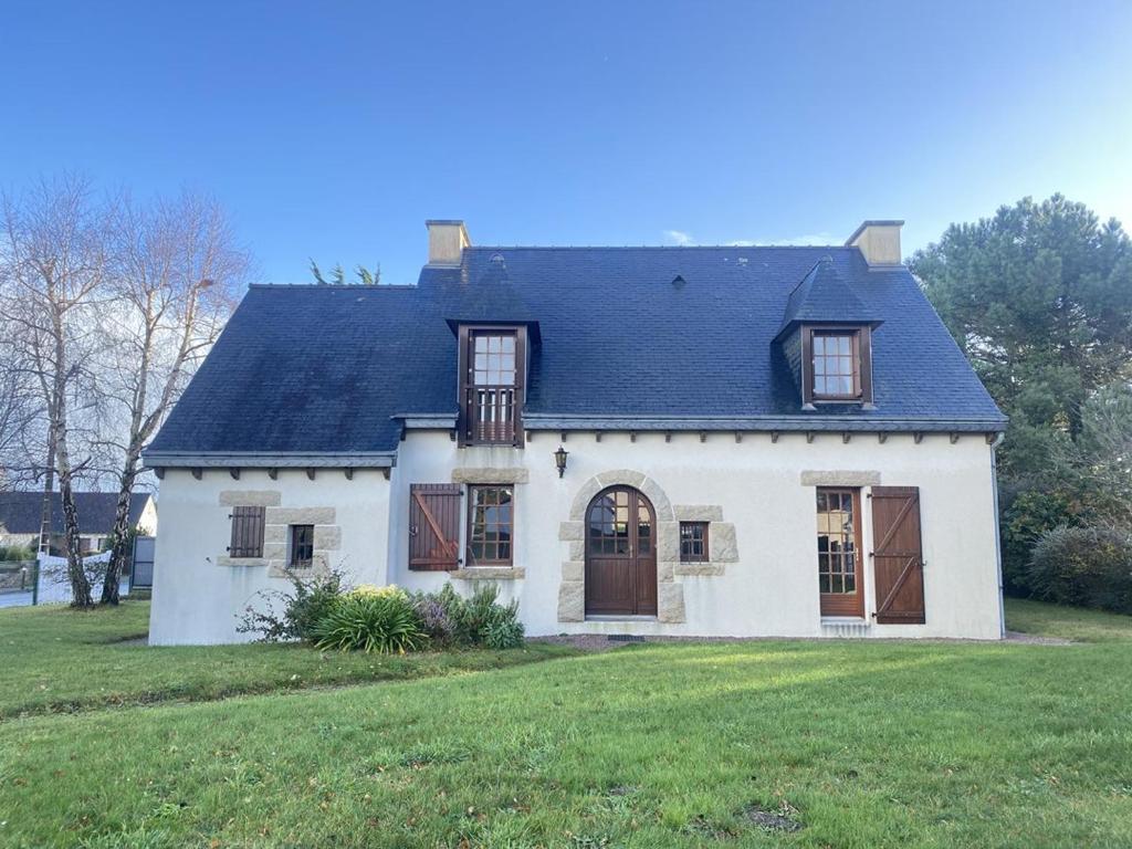 una casa blanca con techo negro y patio en 753 - Belle maison à Erquy à 1km5 des plages et 2km5 du centre en Erquy