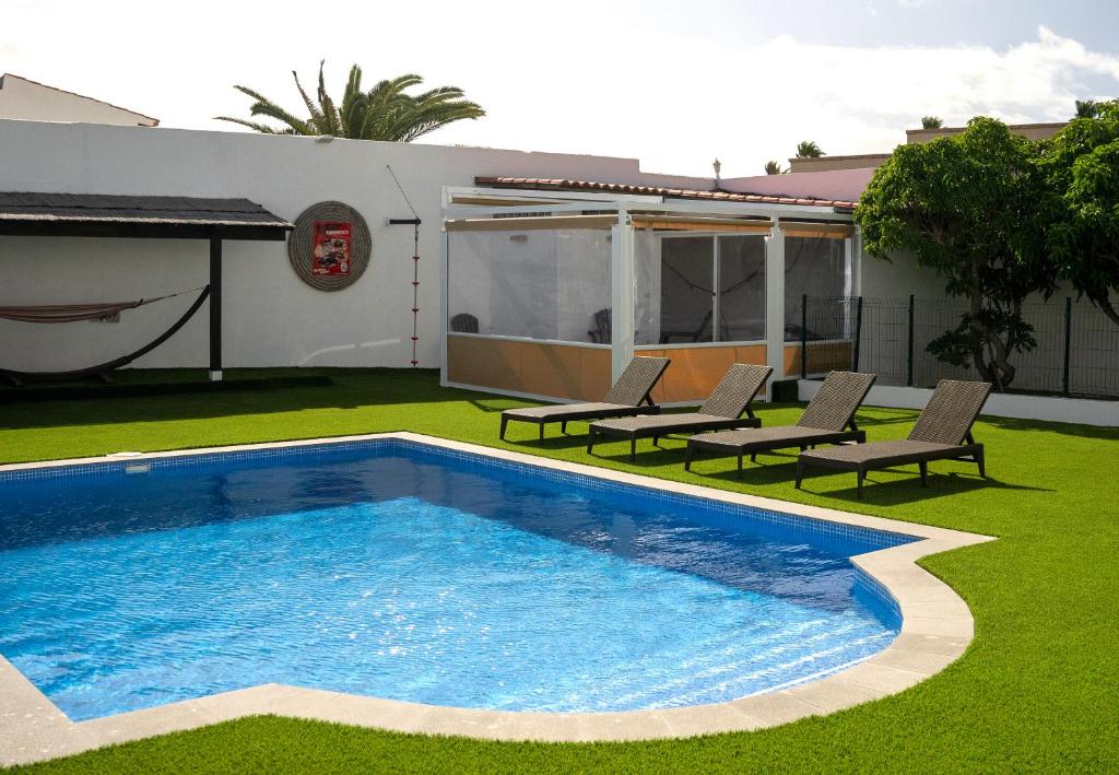 a swimming pool in a yard with chairs and a house at Big Family in La Mareta