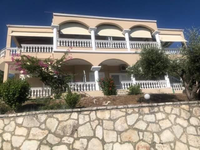 a large house with a stone wall in front of it at Charoula's Apartments in Syvota