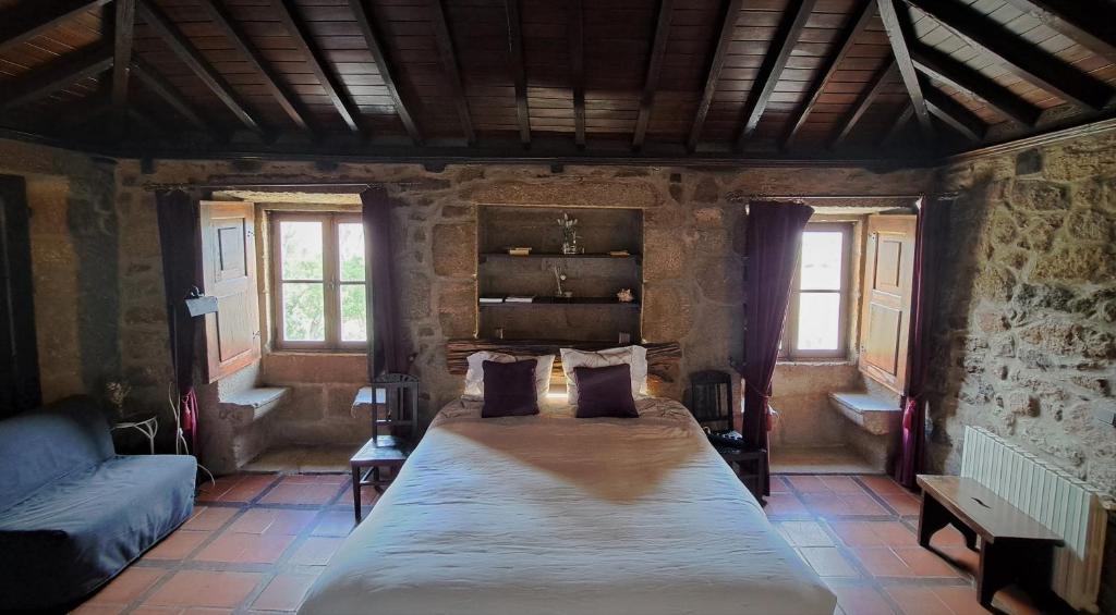 um quarto com uma cama grande num quarto com janelas em Quinta da Mata - Turismo de Habitação em Chaves