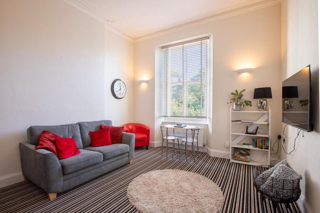 a living room with a gray couch and red pillows at Cosy Flat in Victorian Villa- Parking & Garden in Torquay