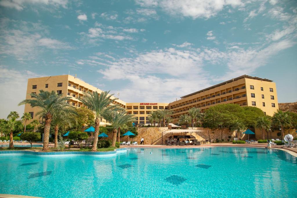 a large swimming pool in front of two buildings at East hotel in Sowayma