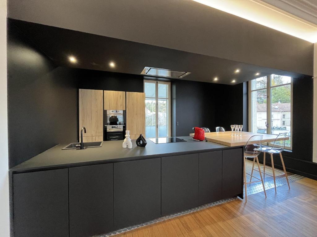 a kitchen with black walls and a kitchen island with a table at L&#39;aristide in Épinal