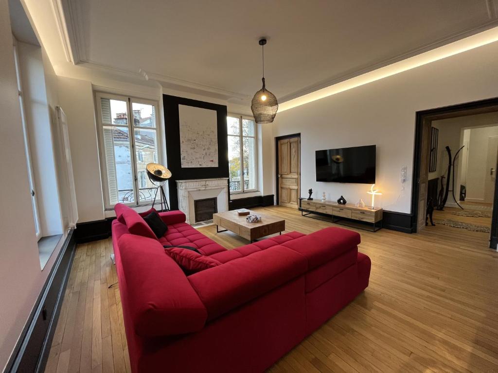 a living room with a red couch and a fireplace at L&#39;aristide in Épinal