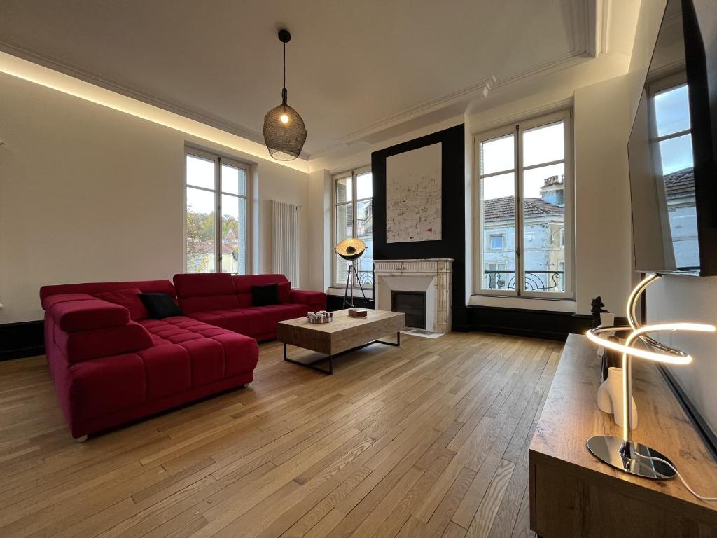 L'aristide في إبينال: غرفة معيشة مع أريكة حمراء ومدفأة