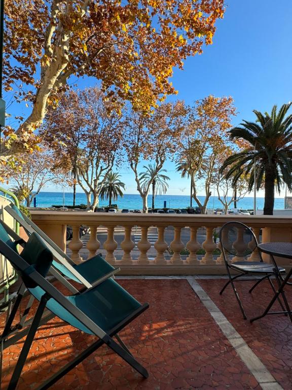 a green chair sitting on a balcony with a view of the ocean at Hotel Pavillon Imperial in Menton