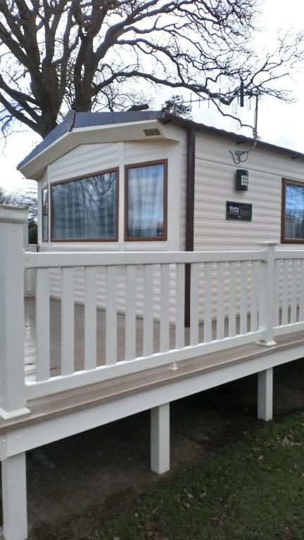 uma pequena casa com uma cerca branca em New Forest Caravan, #108 em New Milton
