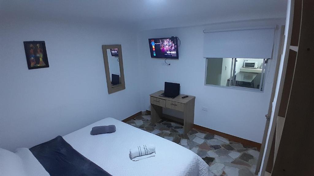 a bedroom with a bed and a tv on the wall at HOSTELFC CORFERIAS in Bogotá
