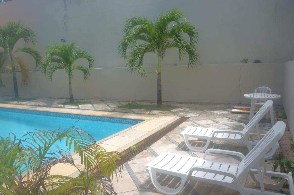 a pool with two lounge chairs and palm trees at Pousada Costa do Calhau in São Luís