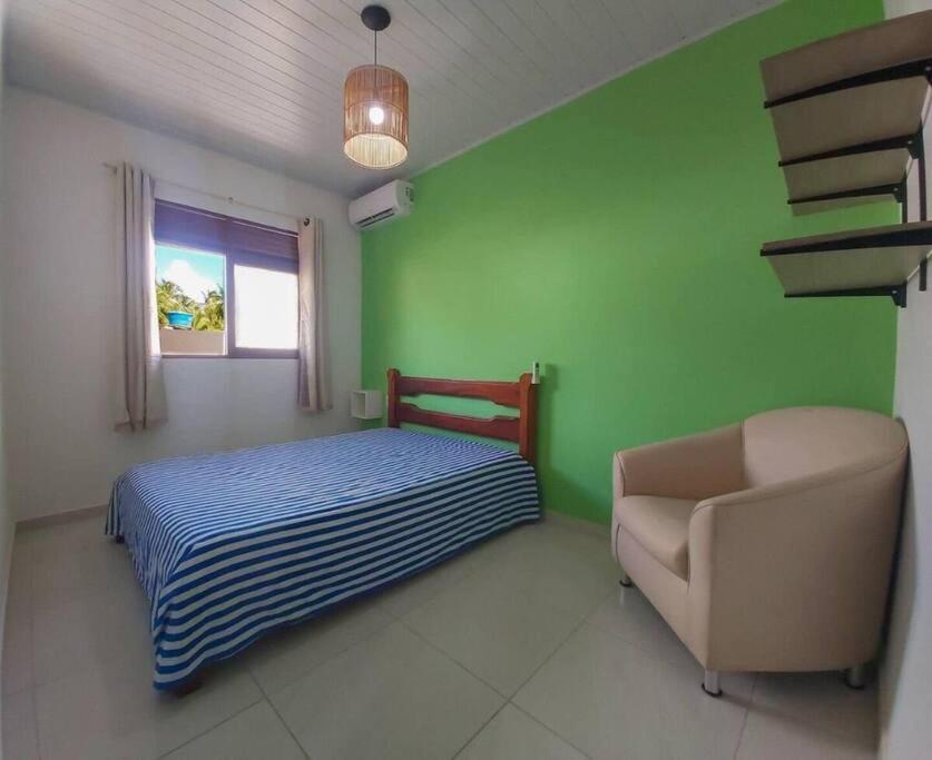 a bedroom with a bed and a chair and a window at Lady Sea Praia do Patacho in Pôrto de Pedras