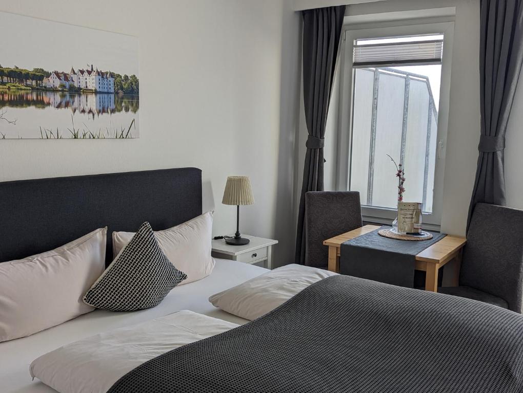 a bedroom with a bed and a chair and a window at Hotel am Wasserschloss Glücksburg in Glücksburg