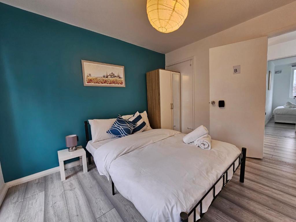 een slaapkamer met een bed en een groene muur bij London Mile End Rooms in Londen