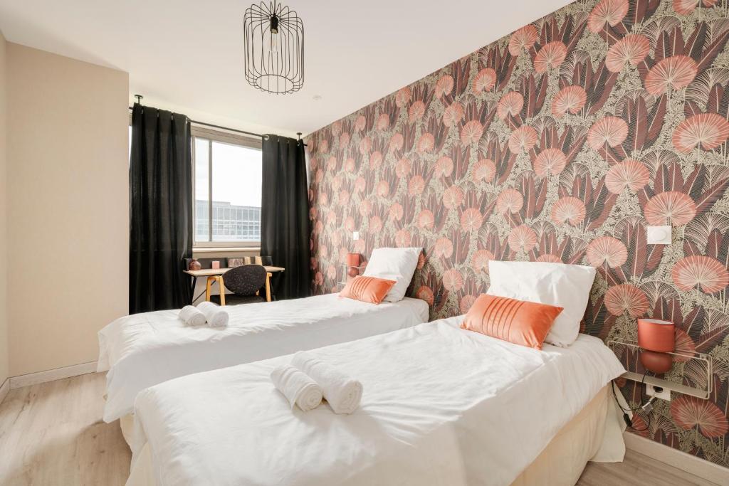 two beds in a room with a floral wallpaper at L'Elégance du centre - Nancy Gare Congrès - PARKING - T3 in Nancy