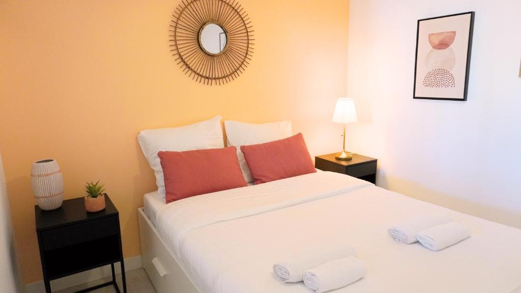 une chambre avec un grand lit blanc avec des oreillers orange dans l'établissement Proche Palais Des Festivals,Croisette - Hyper centre - Palmazur Vacances, à Cannes