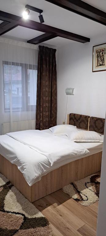 a large bed in a bedroom with a window at Vila Silvana in Moieciu de Jos