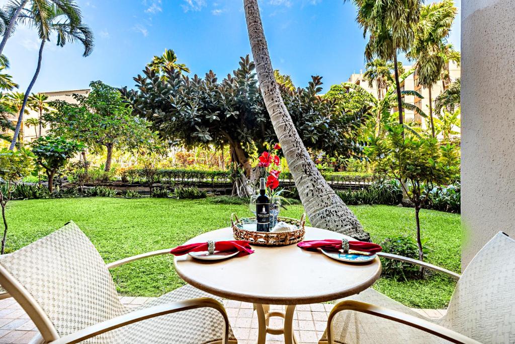 a table and chairs on a patio with palm trees at Kaanapali Shores 144 in Kahana