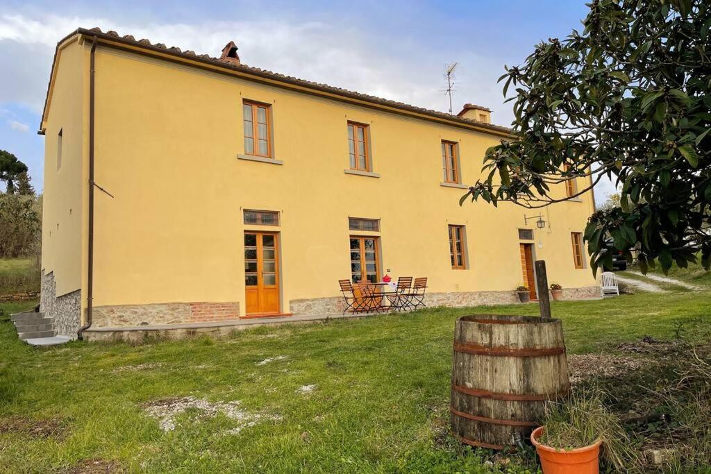 a yellow house with a barrel in front of it at Art Apartment Agriturismo il Vecchio Merlo in Larciano