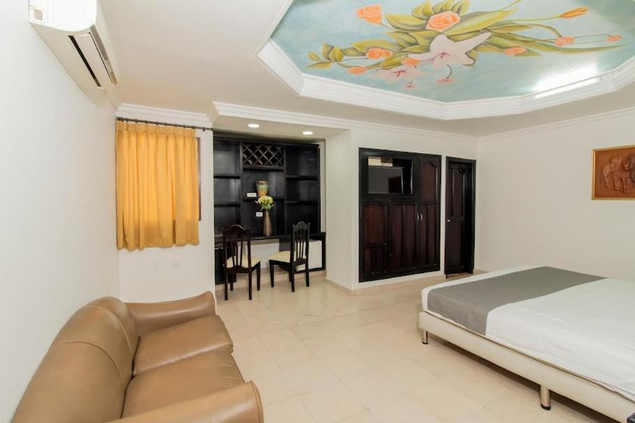 Hotel Caribe Plaza Barranquilla في بارانكويلا: غرفة نوم بسرير واريكة وطاولة