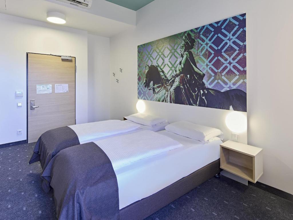 a bedroom with two beds and a painting on the wall at B&B Hotel Dortmund-City in Dortmund