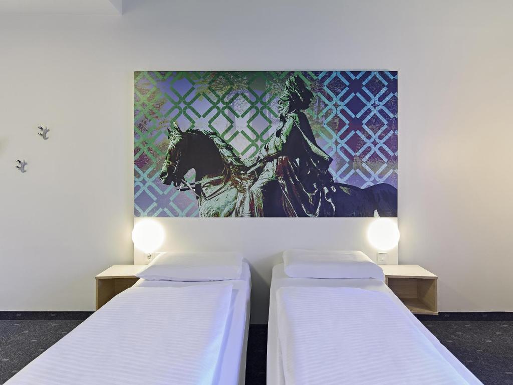 two beds in a room with a painting on the wall at B&B Hotel Dortmund-City in Dortmund
