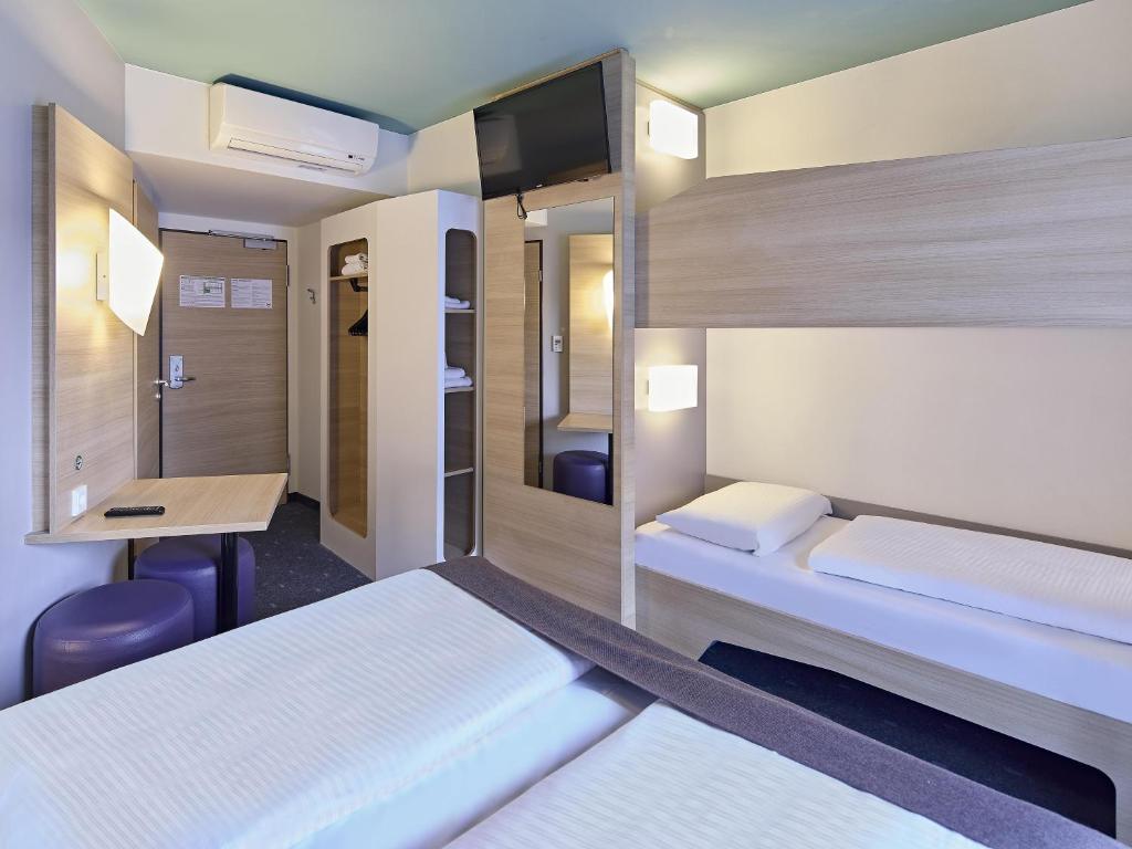a hotel room with two beds and a desk at B&B Hotel Dortmund-City in Dortmund